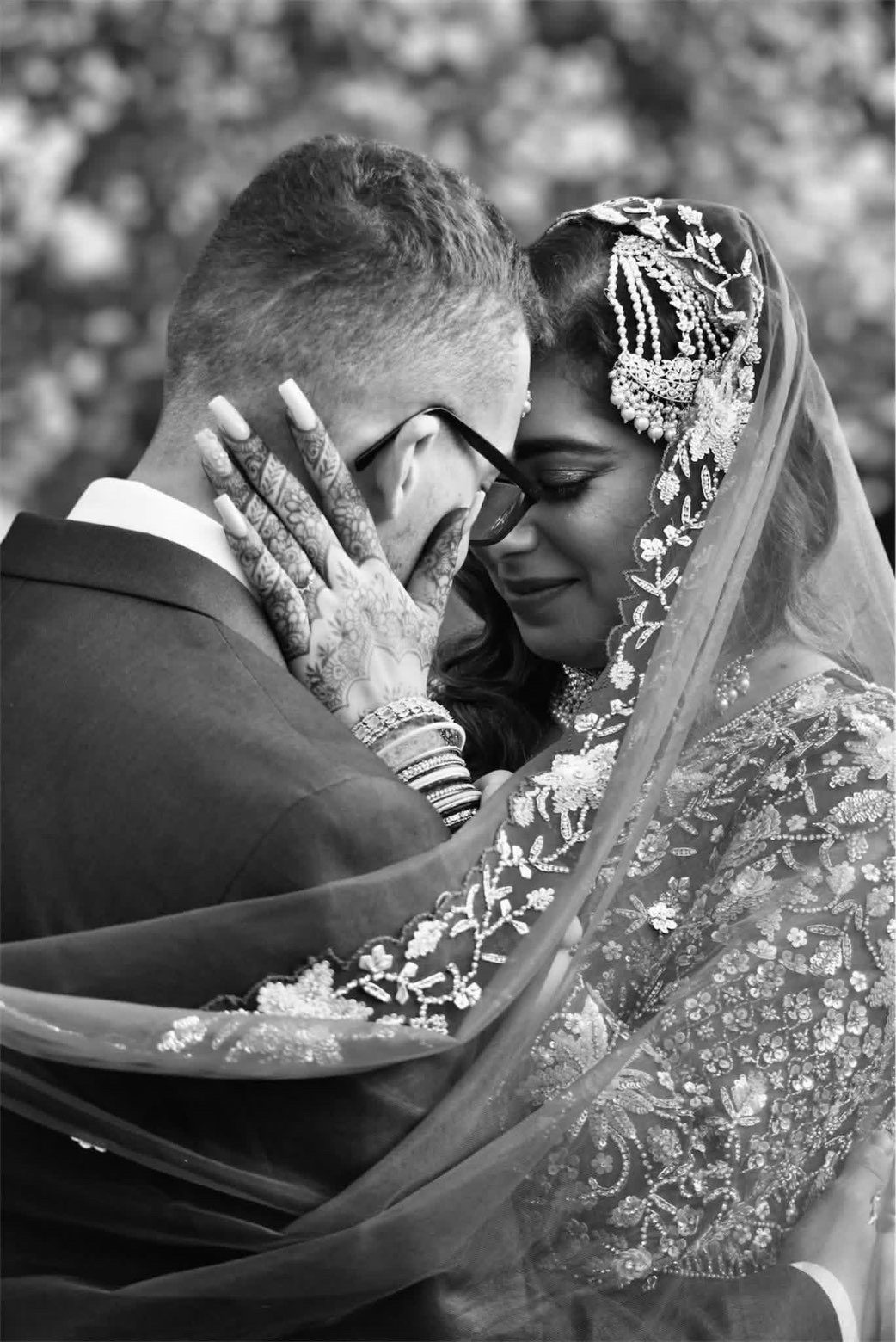 Black and white close-up portrait of a wedding couple beneath a veil