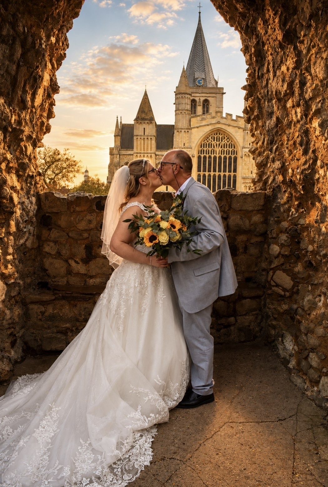 Wedding couple portrait beneath stone architecture