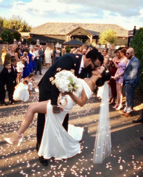 Wedding couple dip kiss surrounded by guests