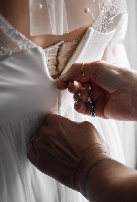 Close detail of a wedding dress being buttoned