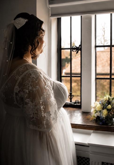 Bride standing by a window before the ceremony
